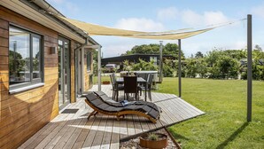 A wooden deck with a sun lounger, a table, and chairs. - Amazing home in Odder with kitchen (Odder)