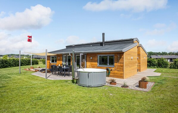 Una casa moderna de madera con un patio, un jacuzzi y una bandera.