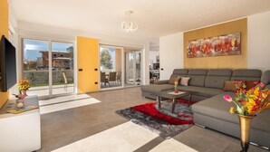 A modern living room with a grey sofa, a coffee table, and a red rug. There is a TV on the left and a painting on the wall. - Gorgeous home in Vodnjan (Vodnjan)