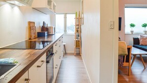 A narrow kitchen with wooden cabinets, a built-in stove, and a small dining area with a table and chairs. - 3 bedroom lovely home in Strömstad (Strömstad)