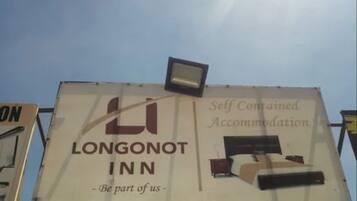 A billboard for Longonot Inn advertising self-contained accommodation with a bed and a nightstand.