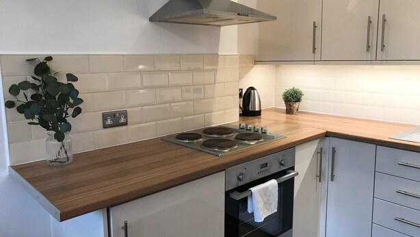 Una cocina moderna con encimera de madera, electrodomésticos de acero inoxidable y armarios blancos.