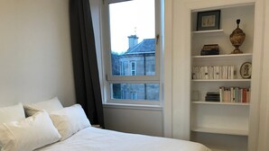 Un dormitorio con una cama grande, una ventana y una estantería.