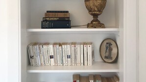 Una estantería con libros, un cuadro enmarcado y una lámpara decorativa.
