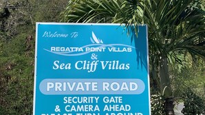 Segnaletica per Regatta Point Villas & Sea Cliff Villas che indica strada privata, cancello di sicurezza e telecamera in arrivo.