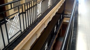 Un intérieur à plusieurs niveaux, doté d’une rambarde en métal noir, de murs en pierre et d’un sol carrelé.