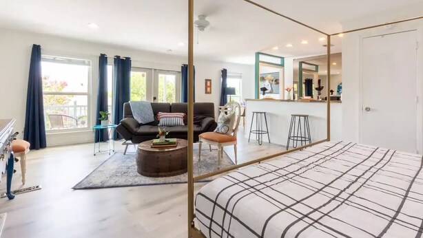 Uma sala moderna com um sofá, poltronas, uma mesa de centro e um espaço de refeições com banquetas.