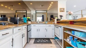 Uma cozinha moderna com armários brancos, bancada de madeira e diversos eletrodomésticos.