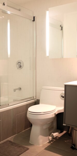 Een bad/douchecombinatie, een haardroger, handdoeken, toiletpapier