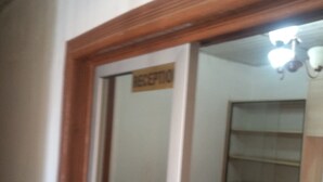 A room with a wooden-framed mirror, a sign above the mirror, a shelf with items, and a ceiling light fixture. - Serene Gates Guest House (Mai Mahiu)