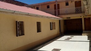 A building with a tiled courtyard, a balcony with a metal railing, and a door with a number '2' sign. - Serene Gates Guest House (Mai Mahiu)