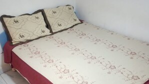 A bed with a floral bedspread and two pillows with a geometric pattern. - Serene Gates Guest House (Mai Mahiu)