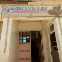 Placa para 'Serene Gates Guest House' com um símbolo de casa e cama, indicando um estabelecimento de hospedagem.