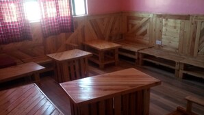 Un intérieur rustique en bois, avec des bancs et des tables disposés pour accueillir les clients.