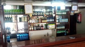Un bar dont les étagères sont remplies de bouteilles et de verres de toutes sortes.
