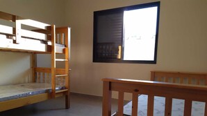 A dormitory room with bunk beds, a window, and a tiled floor.