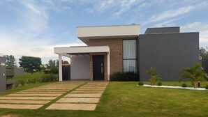 A modern two-story house with a flat roof, a covered porch, and a well-maintained lawn.