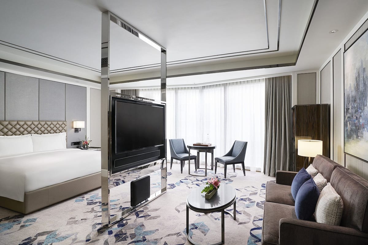 A hotel room with a bed, a TV, a sofa, a coffee table, and a TV stand.