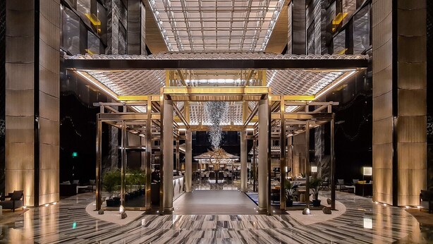 A spacious lobby with a central open area, large pillars, and a ceiling with a grid pattern. - Hotel Okura Manila at Newport World Resorts (Pasay)
