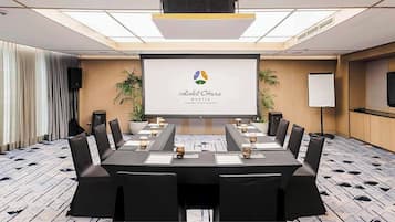 A conference room with a long table, chairs, a projector screen, and a whiteboard.