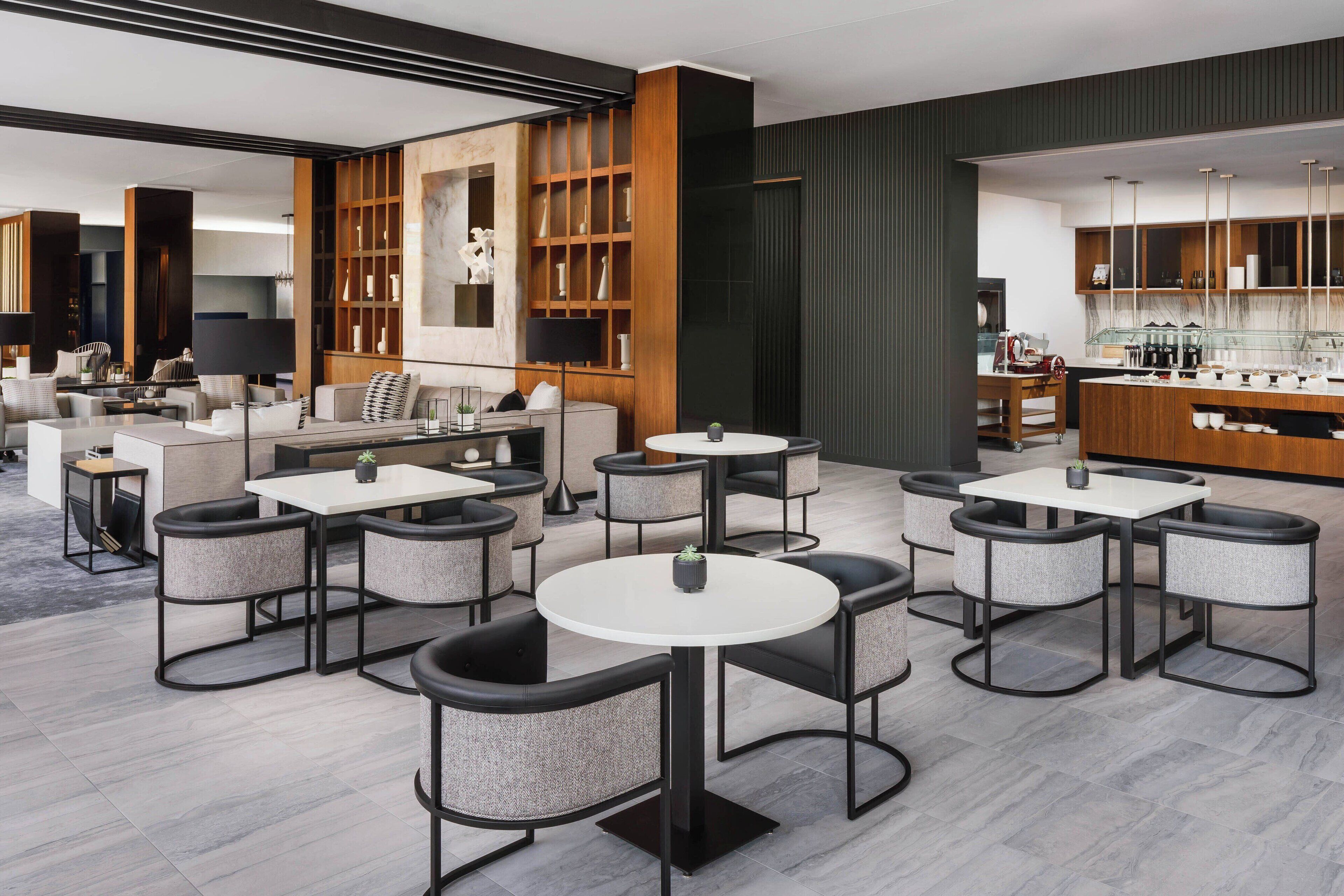 Un moderno vestíbulo de hotel con mesas redondas, sofás y una zona de bar.
