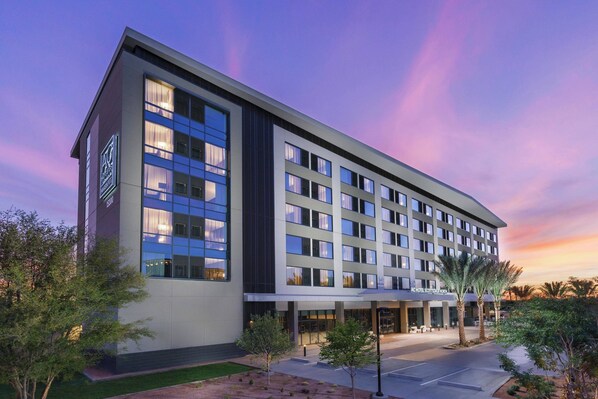 Un hotel moderno con techo plano, ventanas amplias y un patio ajardinado.