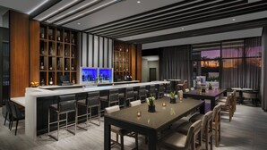 A modern kitchen with a bar area, bar stools, and a dining table with chairs.