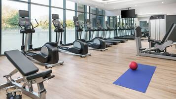 A modern gym with treadmills, elliptical machines, and free weights.