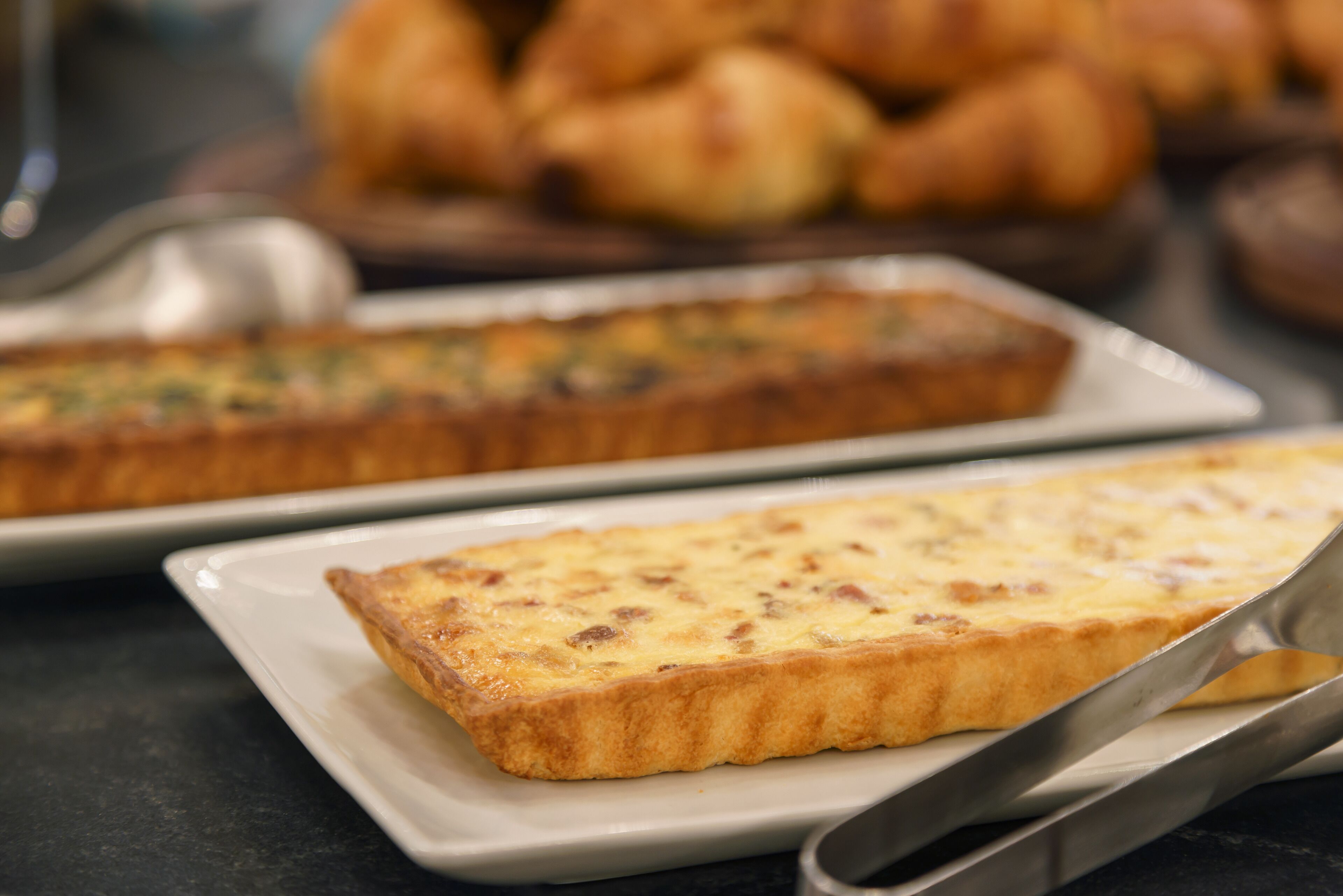Una bandeja de quiches sobre un plato blanco junto a una cuchara.