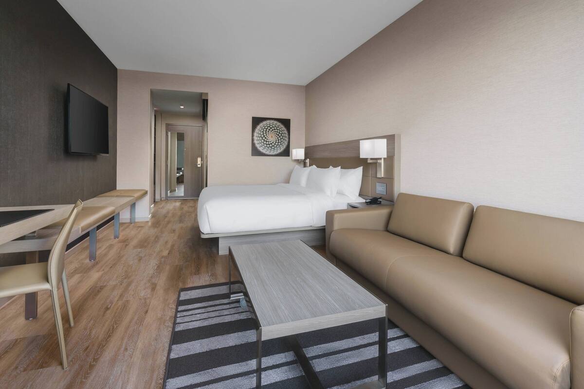 Een moderne hotelkamer met een bed, een bank, een bureau en een televisie.
