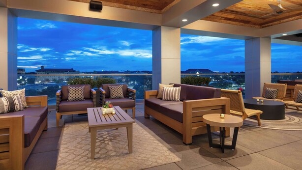 Un espace extérieur aménagé avec du mobilier en bois et de grandes fenêtres offrant une vue sur la ville.
