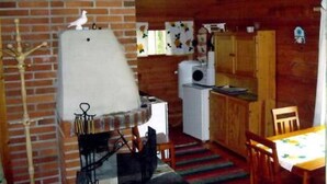 A rustic kitchen with a brick wall, wooden cabinets, a white refrigerator, and a dining area with a table and chairs. - Raanumökki 4 by Interhome (Pello)