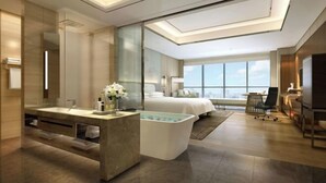A modern hotel room with a large bed, a sitting area with a TV, a bathtub, and a large window offering a city view. - Hengxu International Hotel (Yibin)
