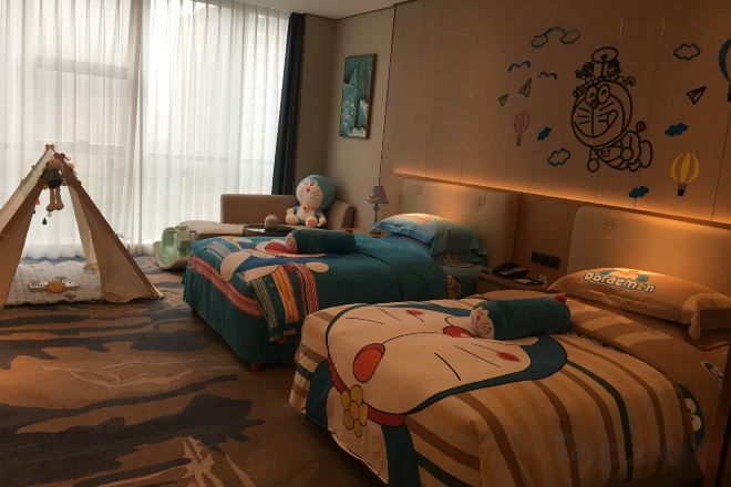 A hotel room with two beds, a tent, and a large window with curtains.