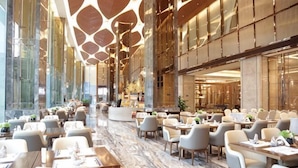A spacious hotel lobby with multiple dining areas, large windows, and a modern ceiling design. - Hengxu International Hotel (Yibin)