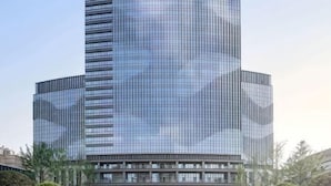 A modern skyscraper with a glass facade, multiple floors, and a prominent central spire. - Hengxu International Hotel (Yibin)