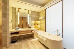 A modern bathroom with a large mirror, a bathtub, and a vanity with a sink. - Hengxu International Hotel (Yibin)