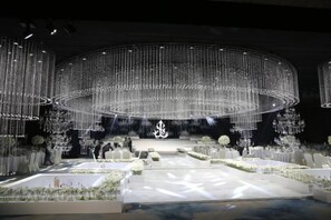 A formal event space with a circular stage, seating arrangements, and decorative lighting. - Hengxu International Hotel (Yibin)