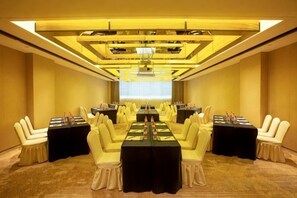 A conference room with multiple tables and chairs, carpeted flooring, and a chandelier. - Hengxu International Hotel (Yibin)