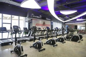 Un gimnasio con cintas de correr, bicicletas estáticas y elípticas.