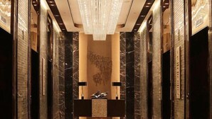 A luxurious lobby with a marble reception desk, a chandelier, and a wall with a unique light installation. - Hengxu International Hotel (Yibin)