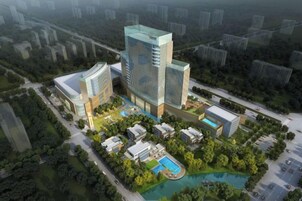 Un hotel moderno de gran altura con varias plantas, una piscina y zonas verdes circundantes.