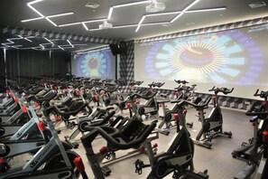 Un gimnasio con varias bicicletas estáticas y cintas de correr dispuestas en filas.