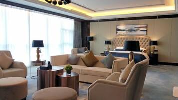 A modern hotel room with a large bed, a sofa, two armchairs, and a coffee table.