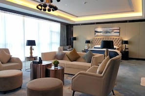 A modern hotel room with a large bed, a sofa, two armchairs, and a coffee table. - Hengxu International Hotel (Yibin)