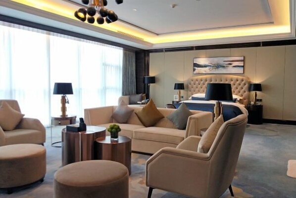 A modern hotel room with a large bed, a sofa, two armchairs, and a coffee table. - Hengxu International Hotel (Yibin)