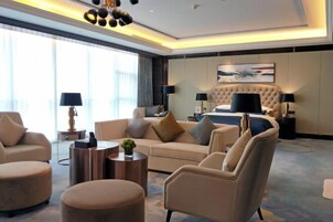 Una habitación de hotel moderna con una cama grande, un sofá, dos sillones y una mesa de centro.
