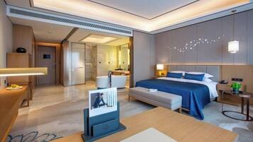 A modern hotel room with a large bed, bedside tables, a desk, and a seating area.