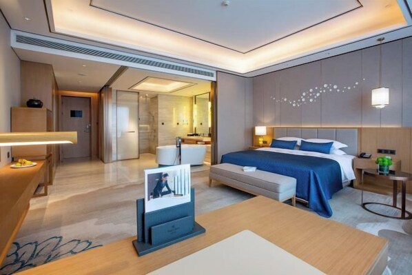 A modern hotel room with a large bed, bedside tables, a desk, and a seating area. - Hengxu International Hotel (Yibin)