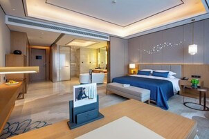 Una habitación de hotel moderna con una cama grande, mesitas de noche, un escritorio y una zona de estar.